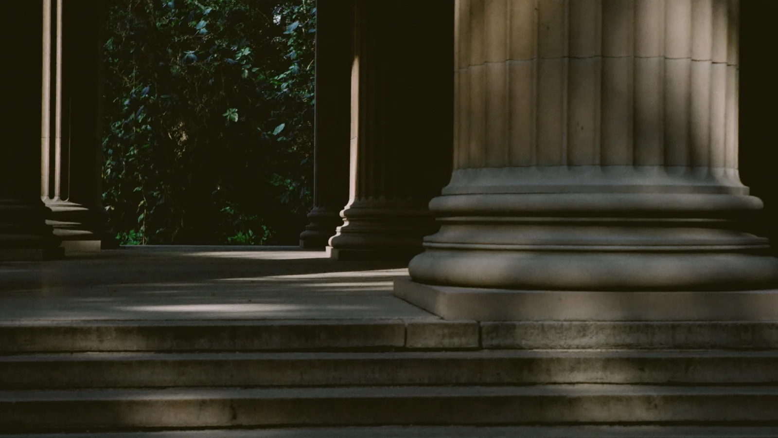 Colonne in pietra e scalinata di un palazzo istituzionale in ombra